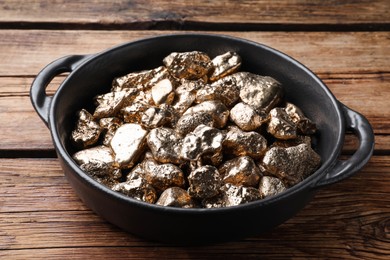 Pan of gold nuggets on wooden table, closeup