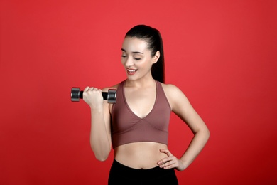 Photo of Woman with dumbbell as girl power symbol on red background. 8 March concept