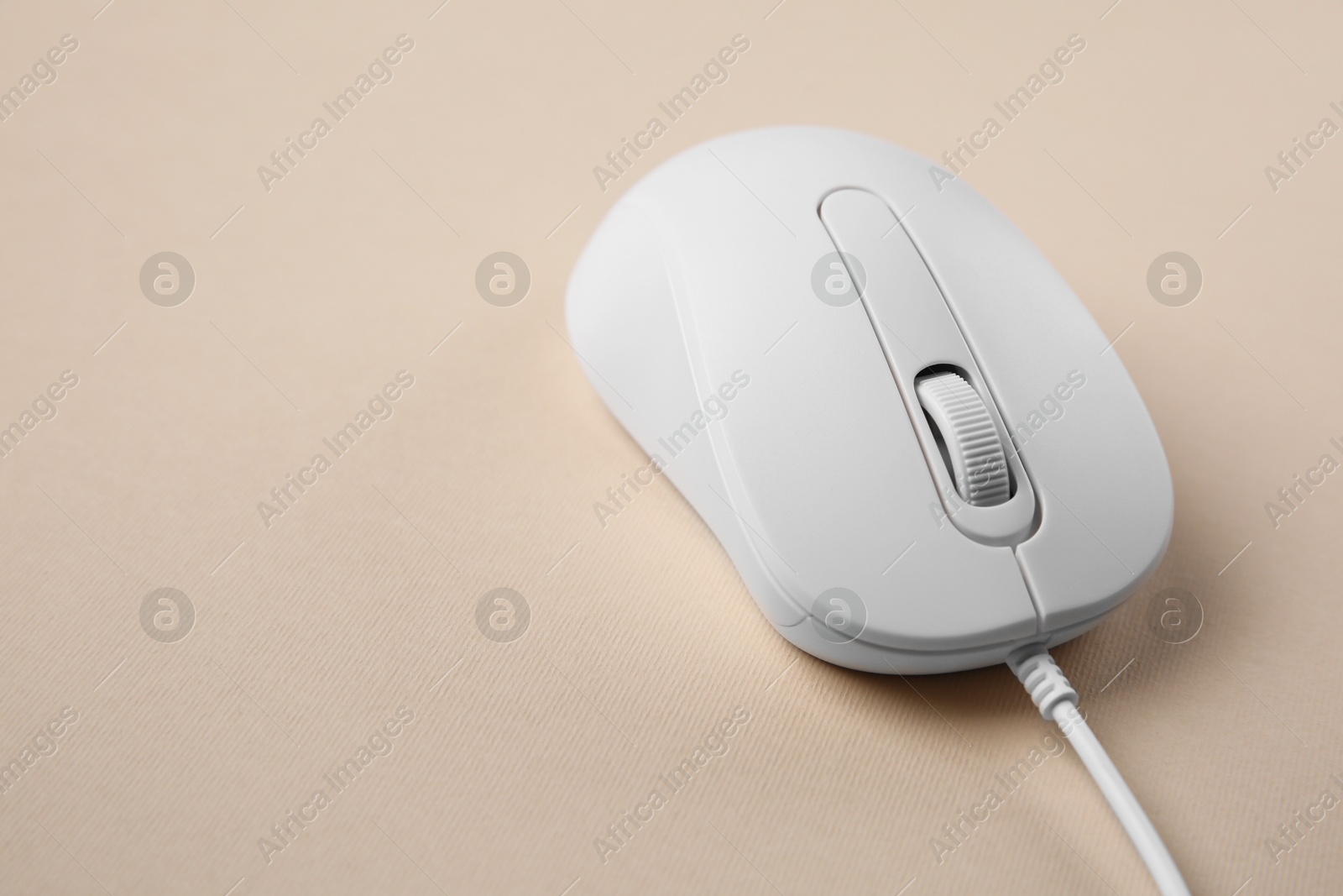 Photo of One wired mouse on beige background, closeup. Space for text
