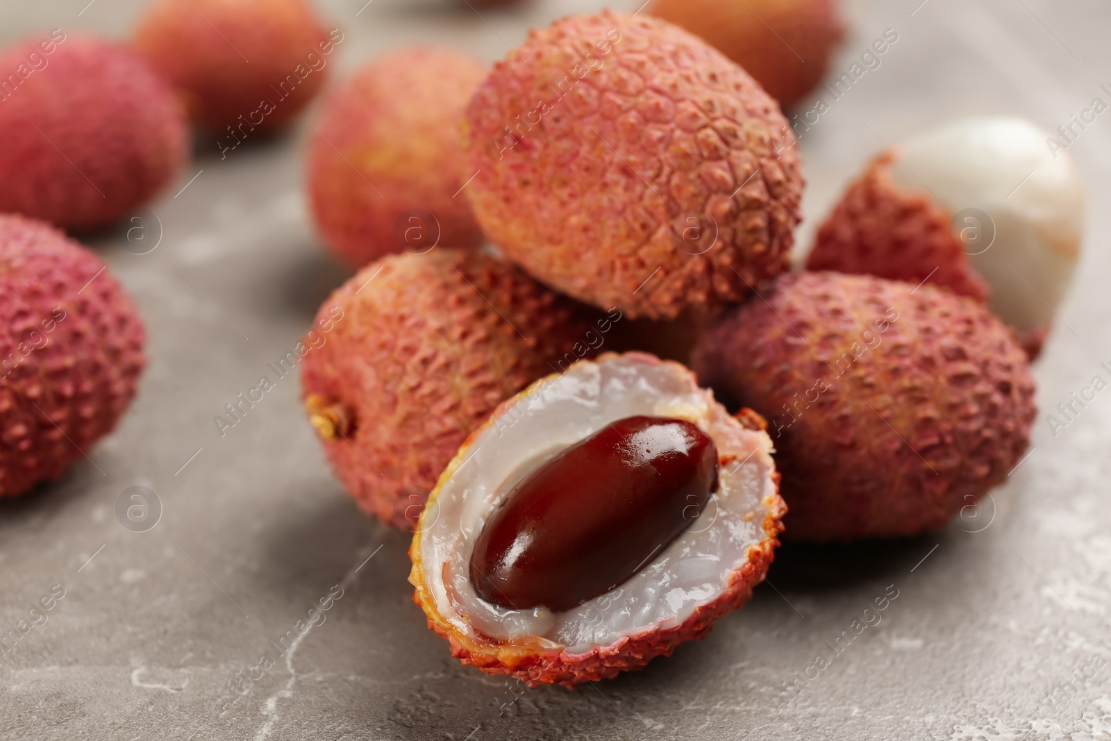 Photo of Fresh ripe lychee fruits on grey table, closeup