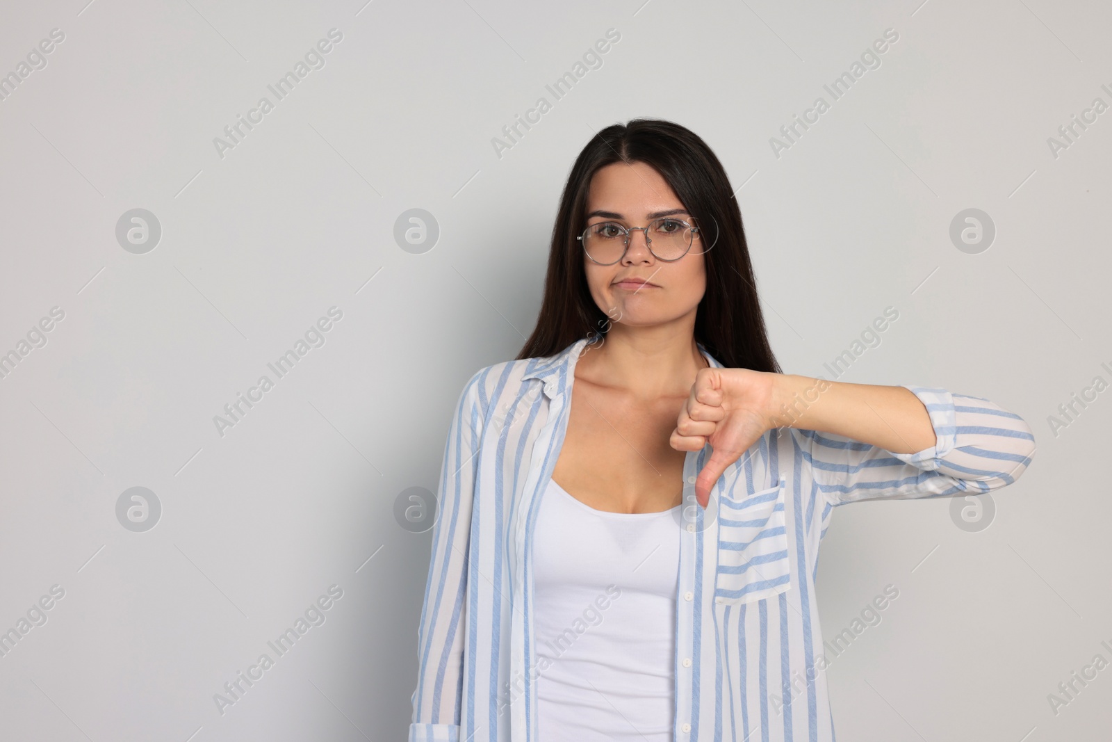 Photo of Young woman showing thumb down on white background, space for text