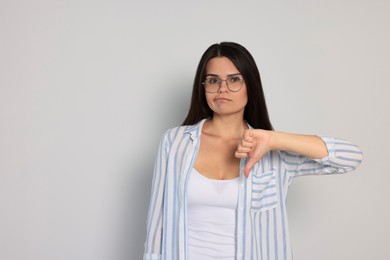 Young woman showing thumb down on white background, space for text