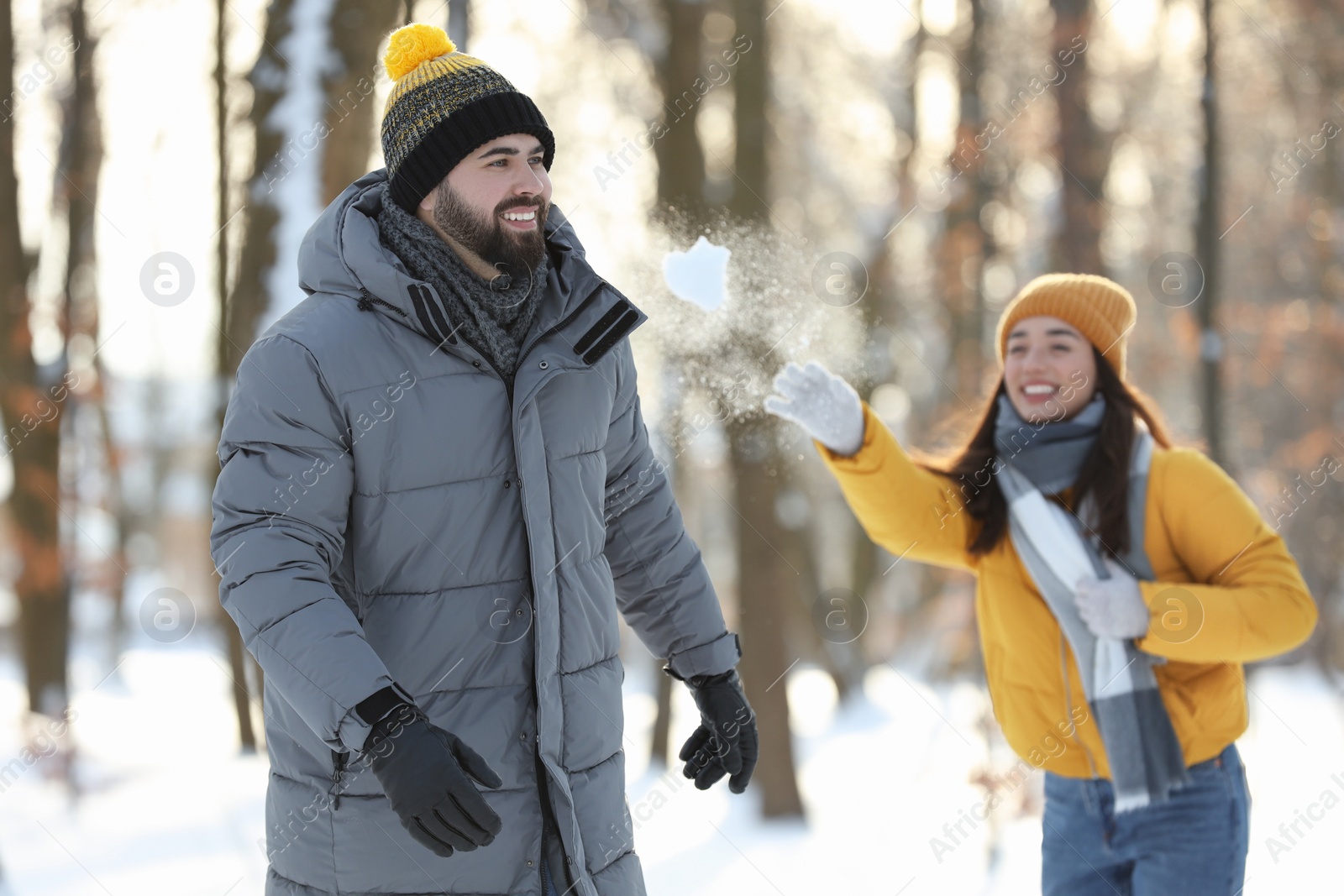 Photo of Happy couple playing snowballs on winter day outdoors