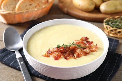 Photo of Tasty potato soup with bacon and rosemary in bowl served on wooden table