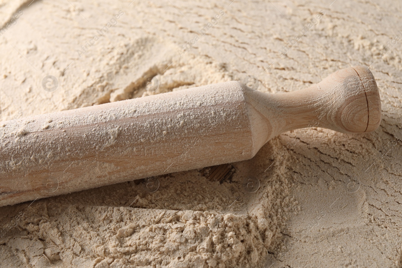 Photo of Flour and rolling pin on table, closeup