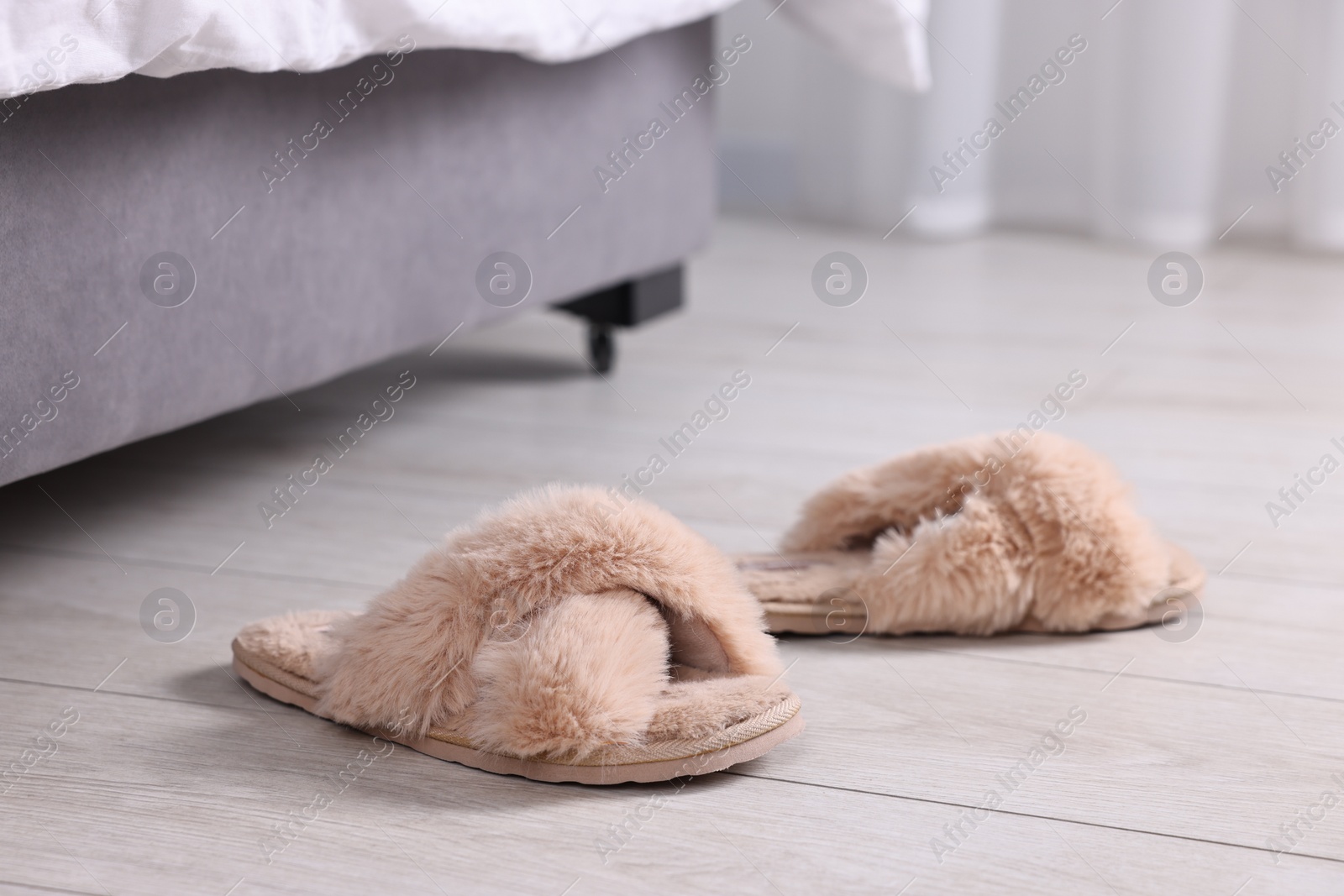 Photo of Beige soft slippers on light wooden floor at home