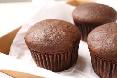 Photo of Delicious fresh chocolate cupcakes in box, closeup