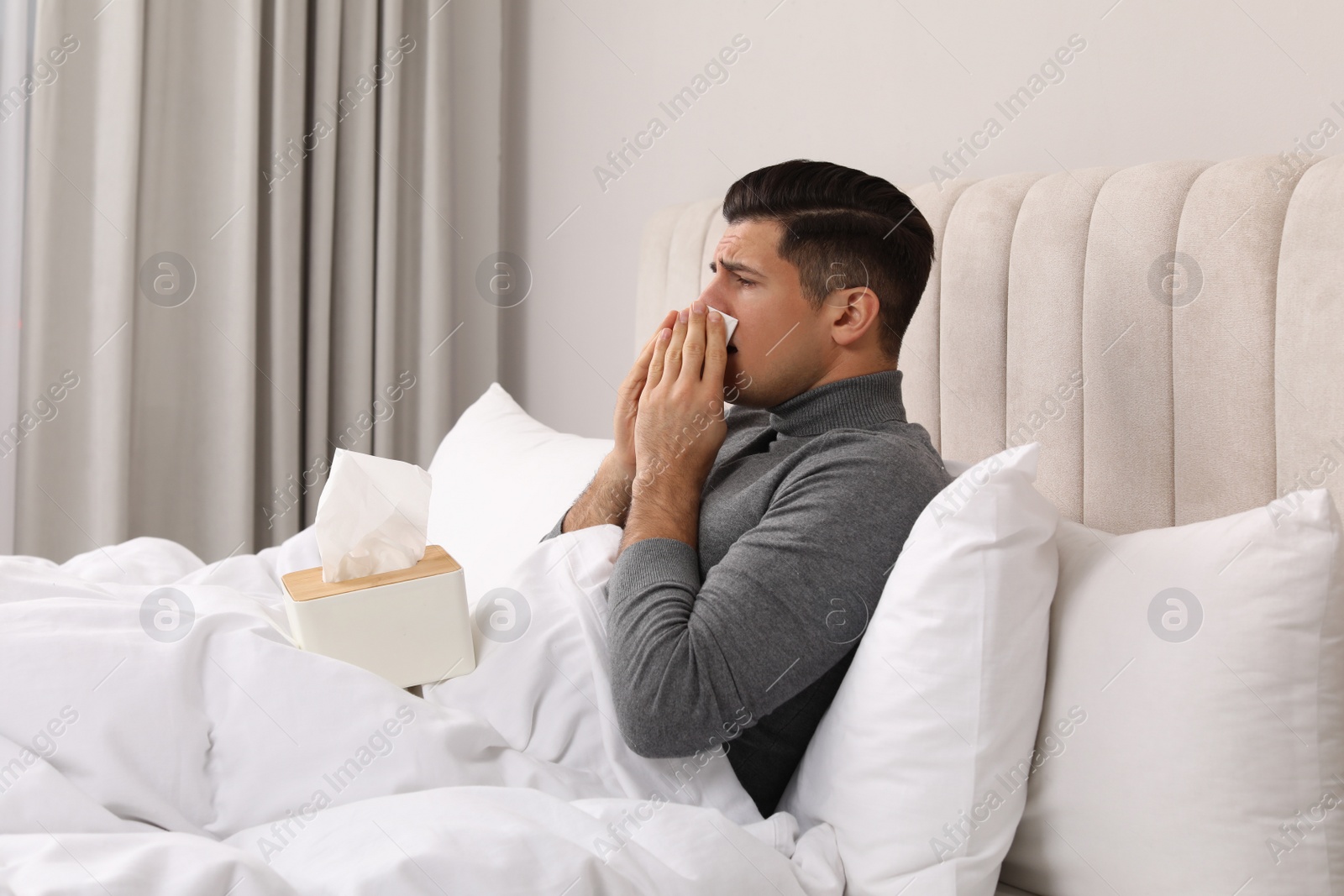 Photo of Sick man with box of paper tissues suffering from cold in bed at home