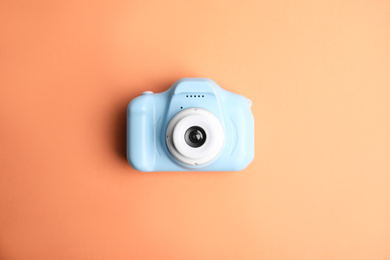 Photo of Light blue toy camera on orange background, top view. Future photographer
