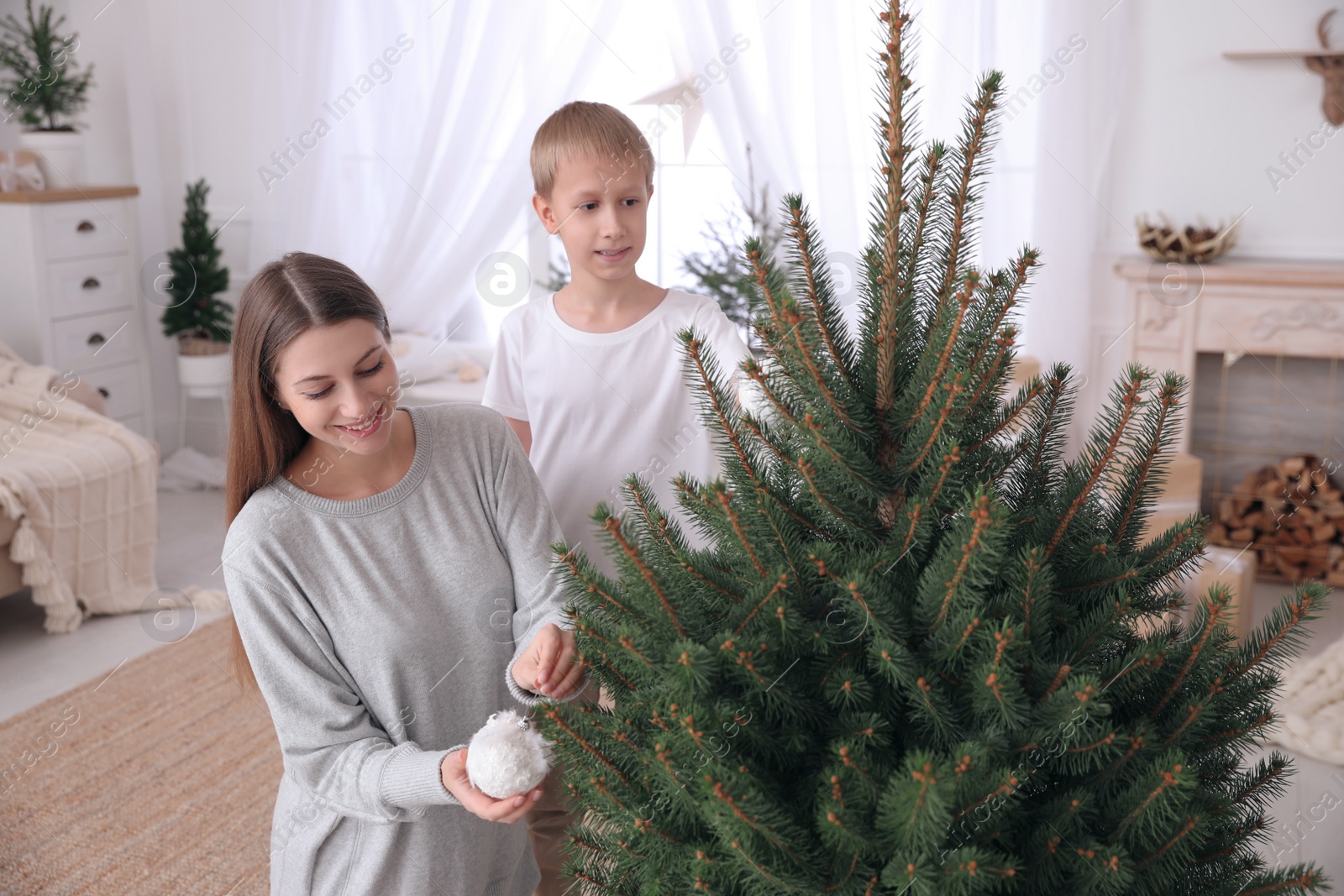 Photo of Happy mother with her cute son decorating Christmas tree together at home