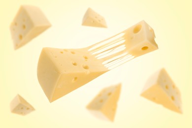 Pieces of cheese falling on yellow background