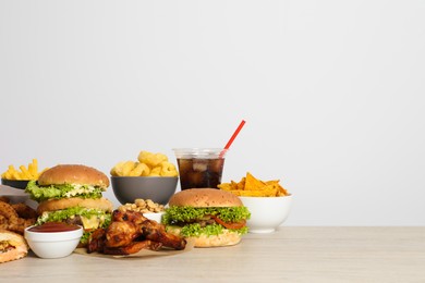 Photo of French fries, burgers and other fast food on wooden table against white background