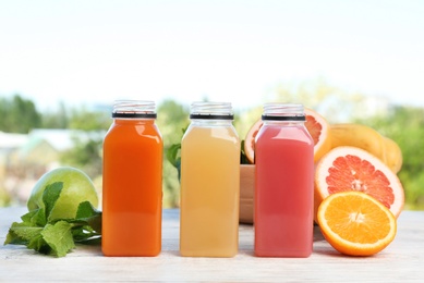 Photo of Bottles with tasty juices and ingredients on table