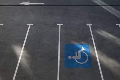 Image of Car parking lot with white marking lines and wheelchair symbol outdoors, above view