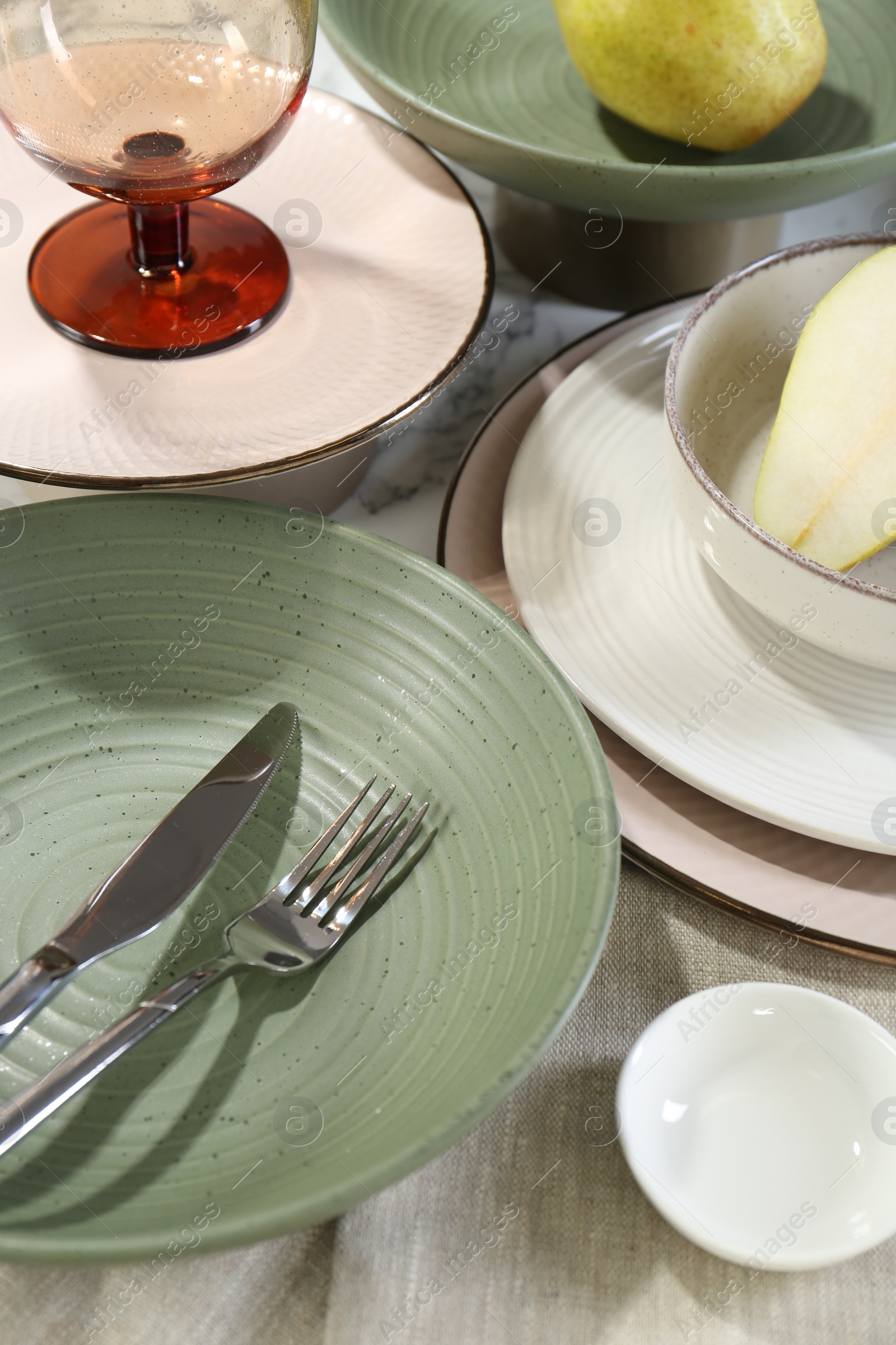 Photo of Stylish ceramic plates, glass, cutlery and pears on white marble table