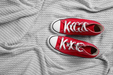 Pair of new stylish red sneakers on light grey fabric, flat lay. Space for text