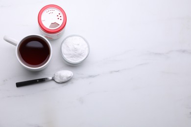 Photo of Sweet fructose powder and cup of tea on white marble table, flat lay. Space for text