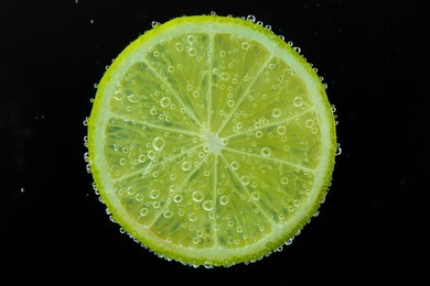 Photo of Slice of lime in sparkling water on black background. Citrus soda
