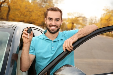 Young man holding car key near auto. Driving license test