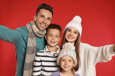 Photo of Happy family in warm clothes on red background. Winter season