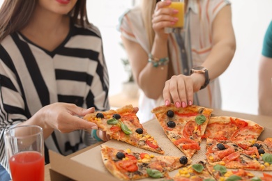 Photo of Young people eating delicious pizza at table, closeup