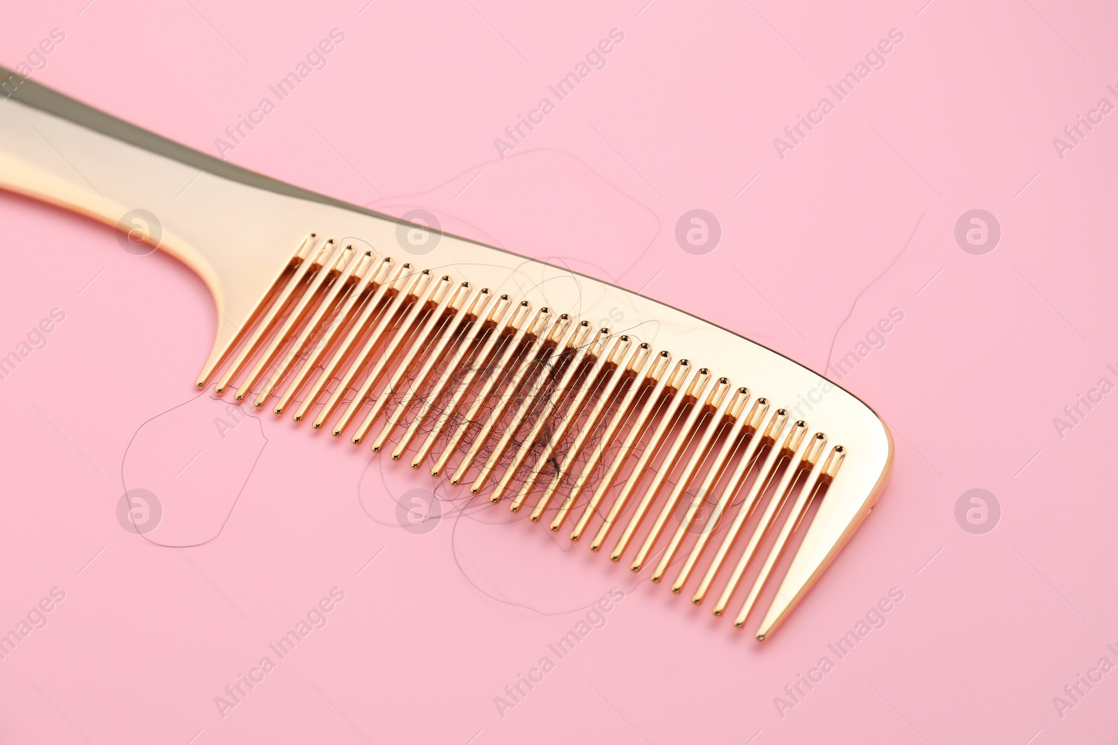 Photo of Comb with lost hair on pink background