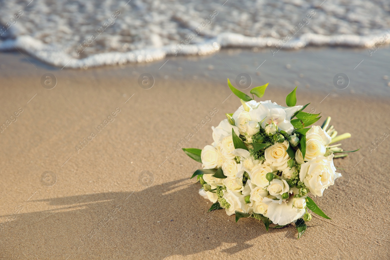 Photo of Beautiful wedding bouquet on sandy beach near sea