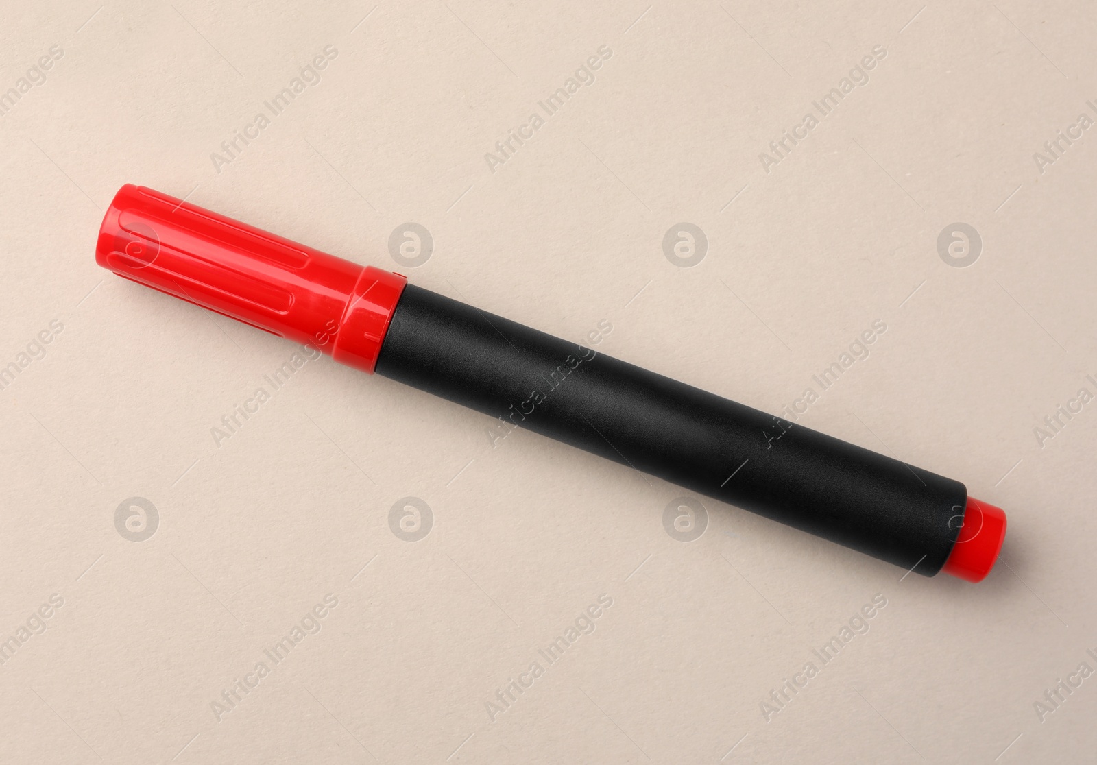 Photo of Bright red marker on beige background, top view