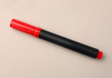Bright red marker on beige background, top view