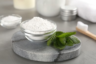 Tooth powder and mint on grey table, closeup