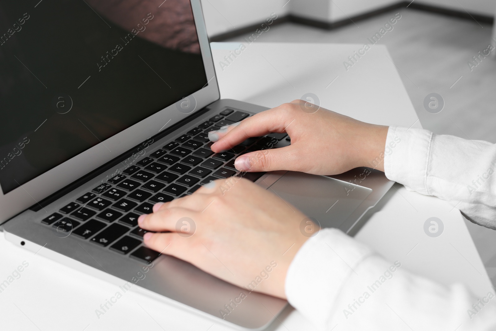 Photo of Woman working on laptop at white table in office, closeup
