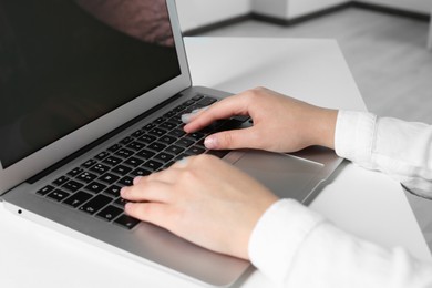 Photo of Woman working on laptop at white table in office, closeup