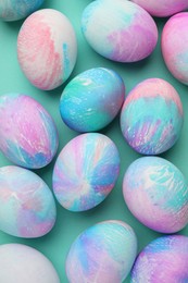 Photo of Many decorated Easter eggs on turquoise background, flat lay