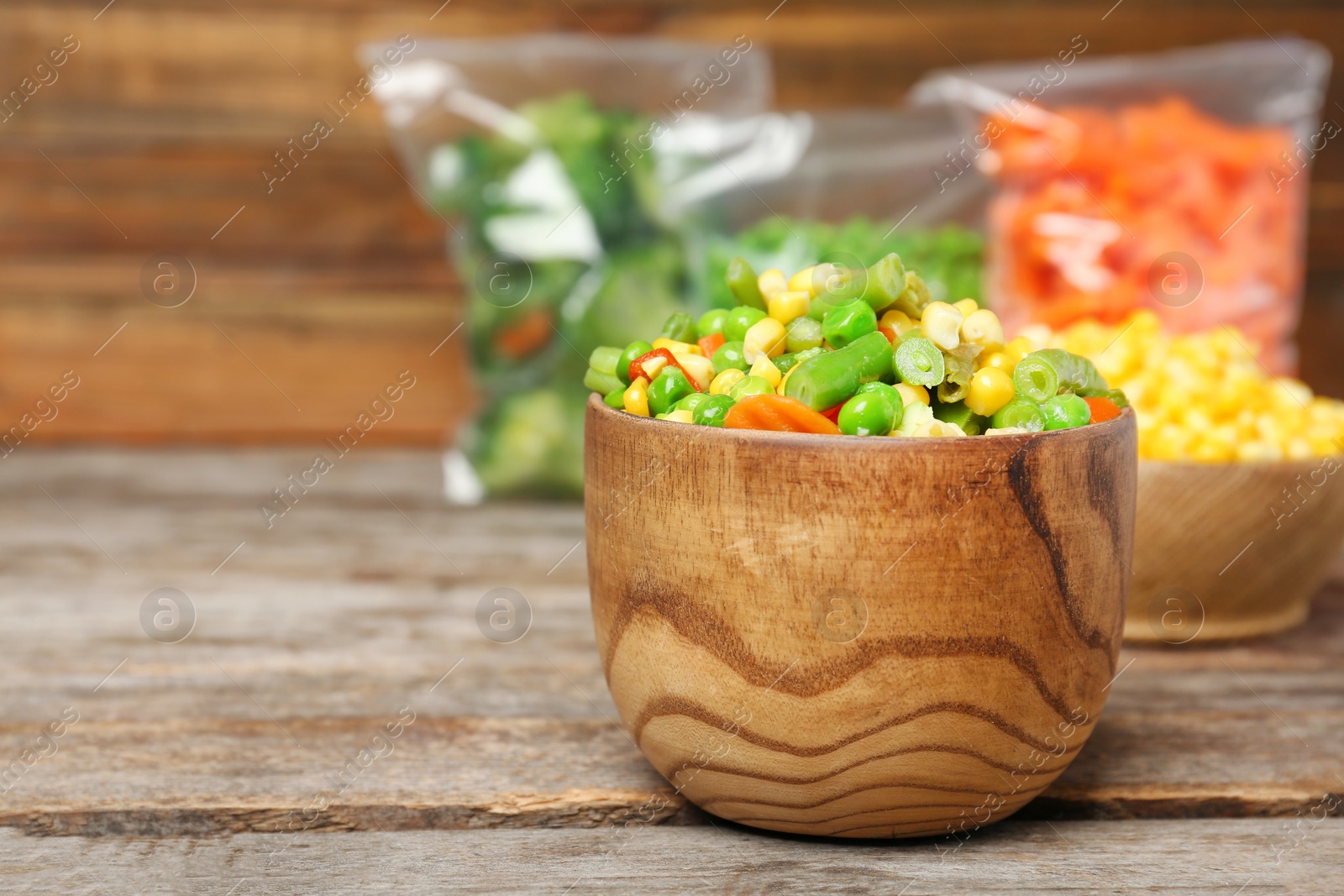 Photo of Bowl with mix of frozen vegetables on wooden table