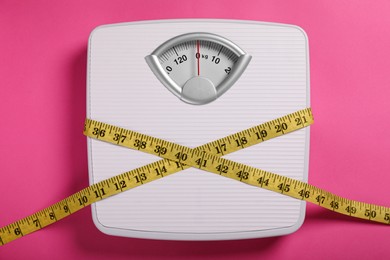 Photo of Weight loss concept. Scales and measuring tape on pink background, top view