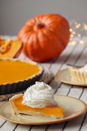 Piece of fresh homemade pumpkin pie with whipped cream on table