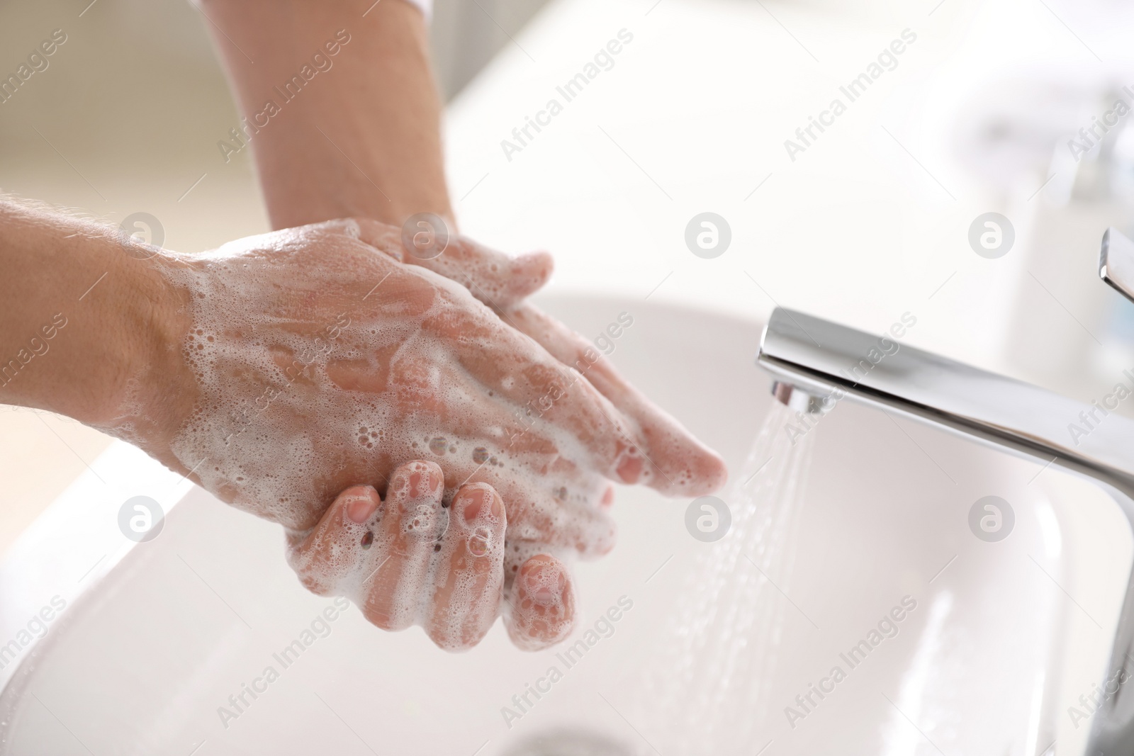 Photo of Man washing hands with soap over sink in bathroom, closeup