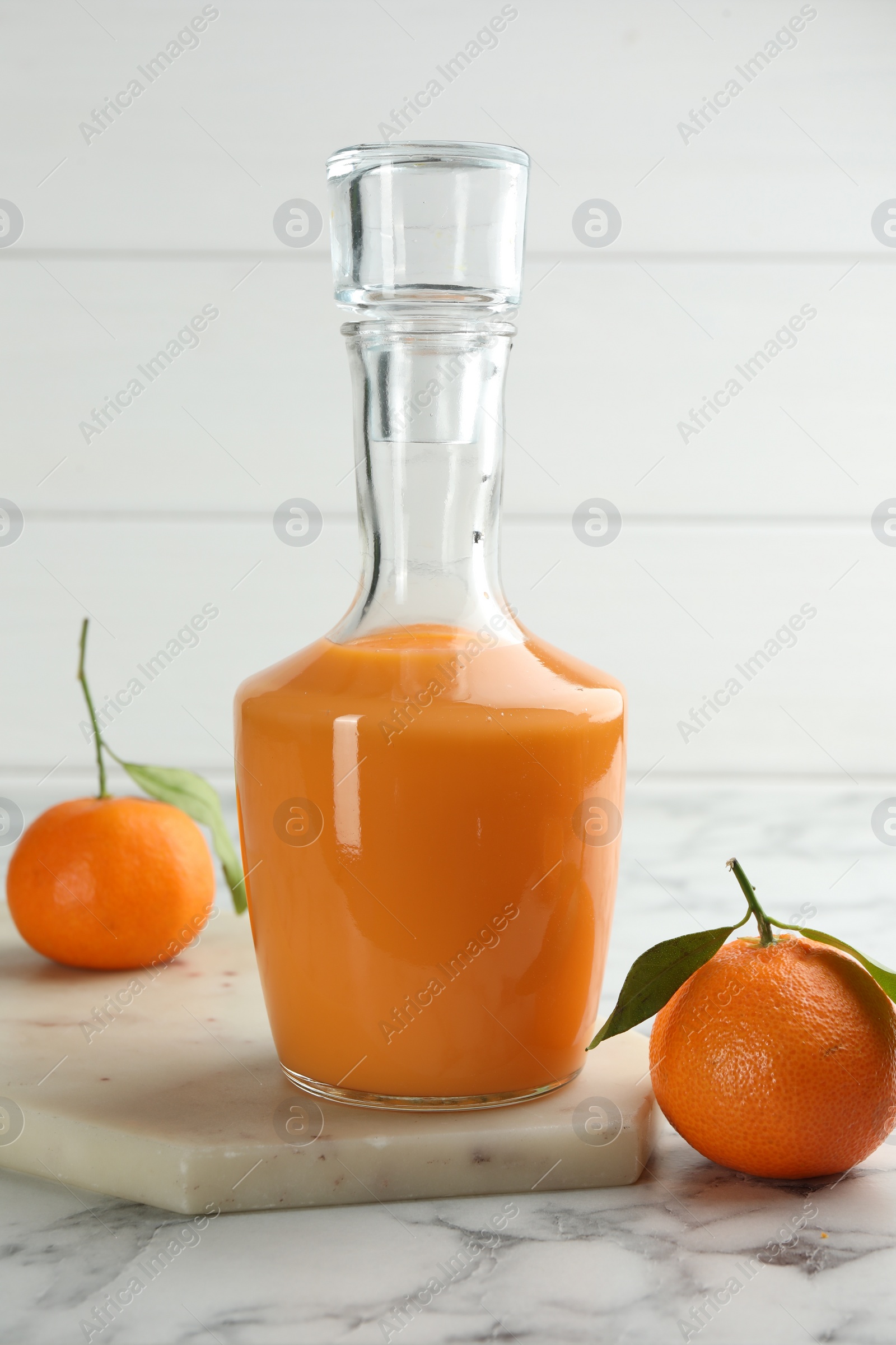 Photo of Delicious tangerine liqueur and fresh fruits on white marble table