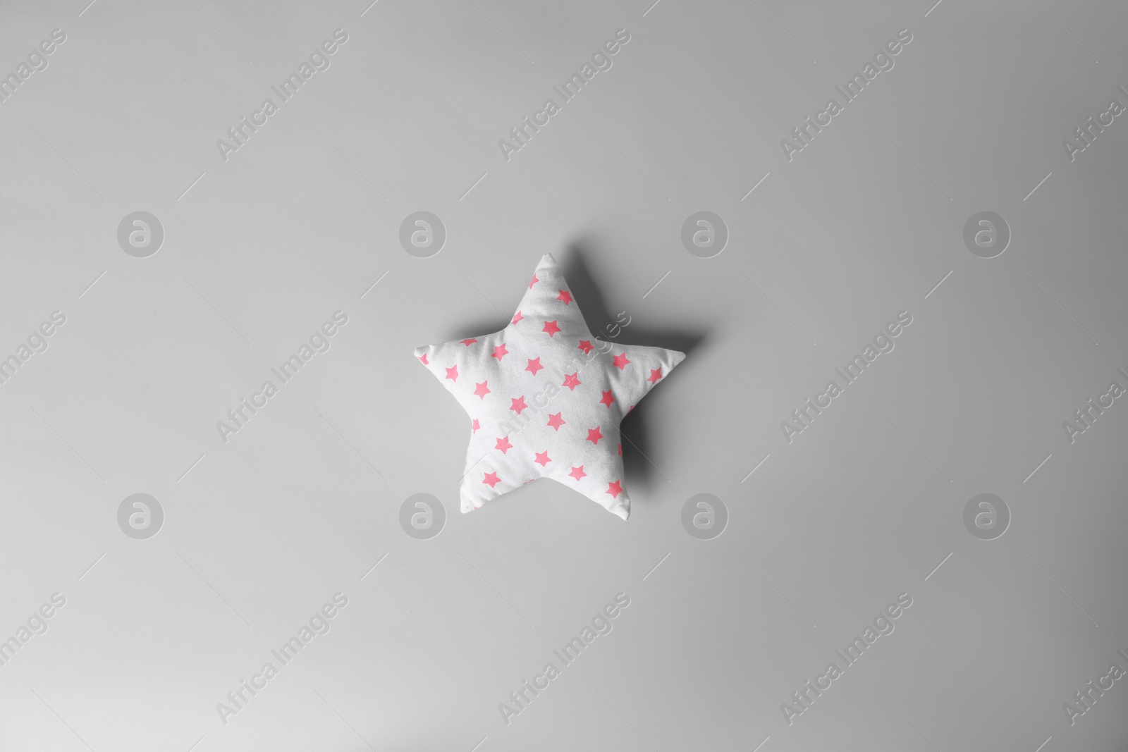 Photo of Soft pillow in shape of star on light background