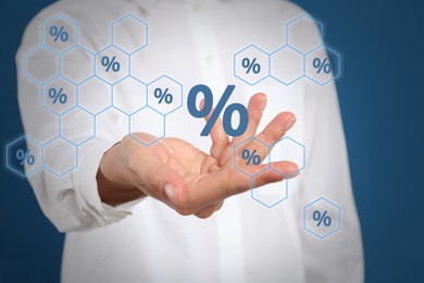 Image of Woman showing virtual percent sign on blue background, closeup. Discount concept
