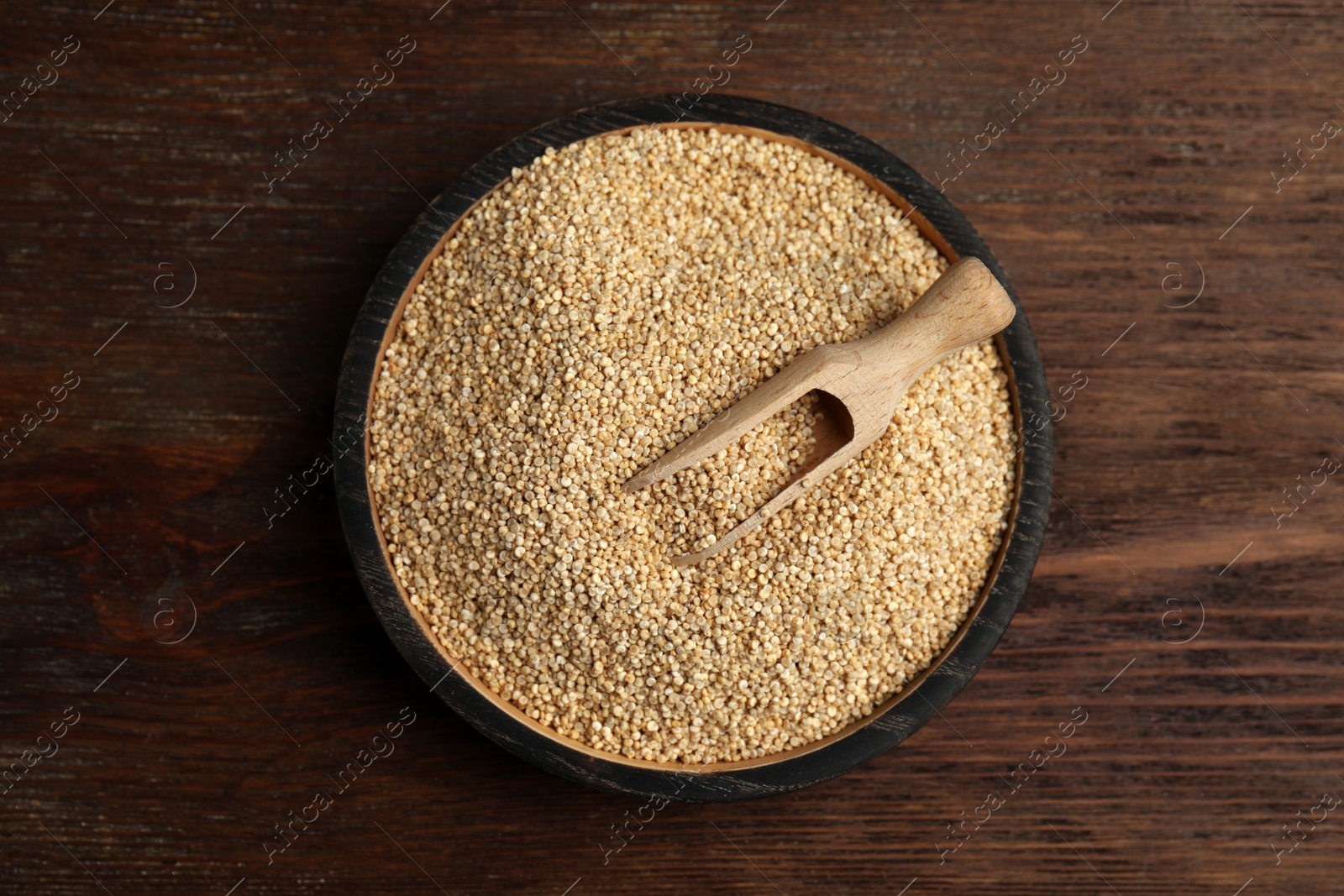 Photo of Plate with white quinoa and scoop on wooden table, top view