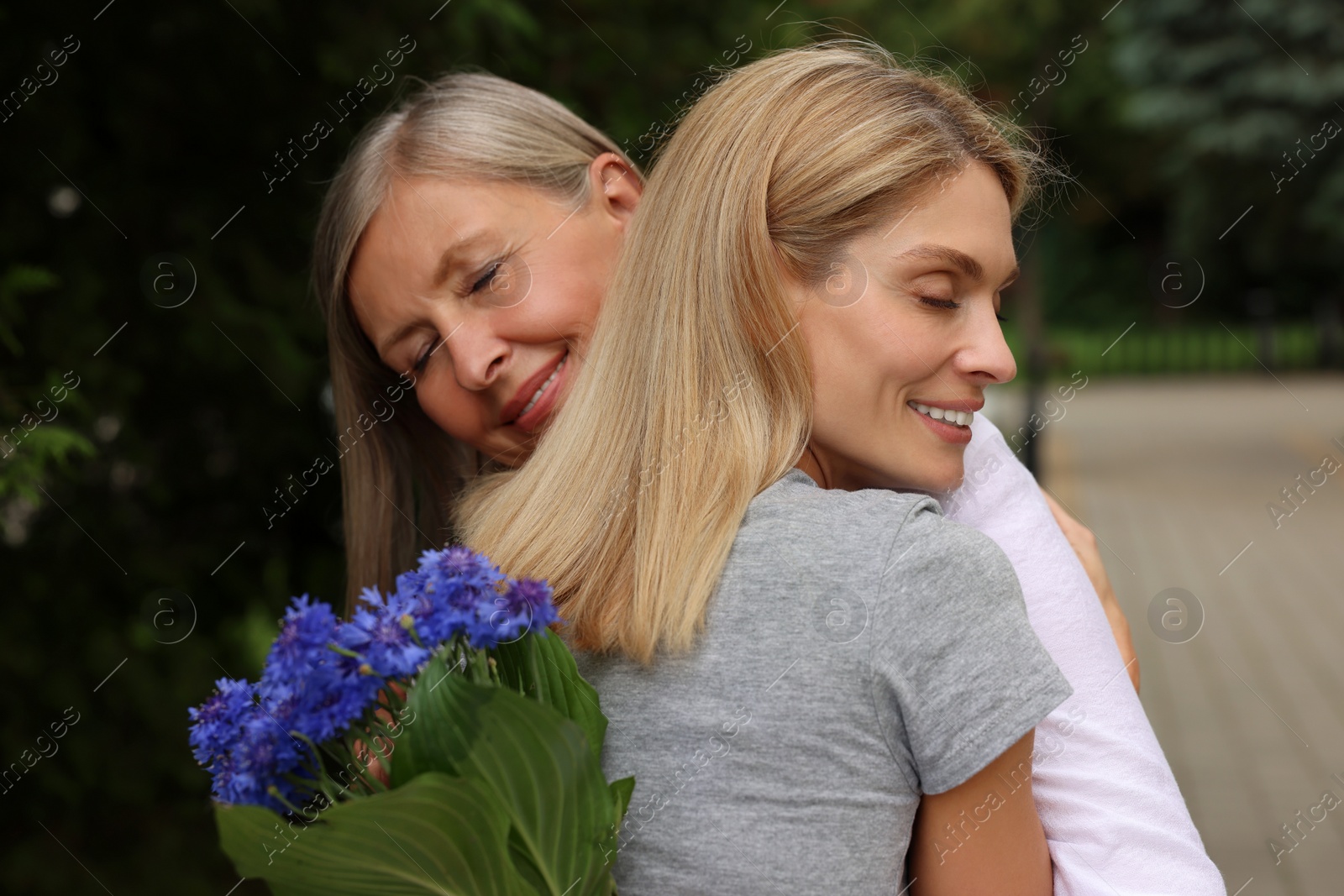 Photo of Happy mature mother and her daughter hugging outdoors