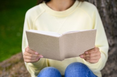Woman reading book in park, closeup view
