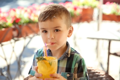 Photo of Cute boy with glass of natural lemonade in cafe