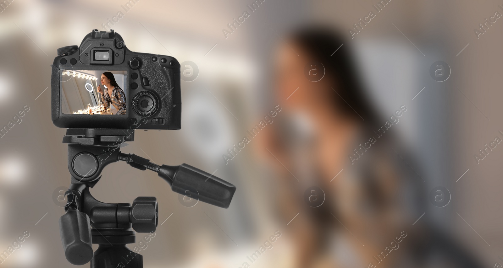 Image of Young woman applying make up, selective focus on camera display