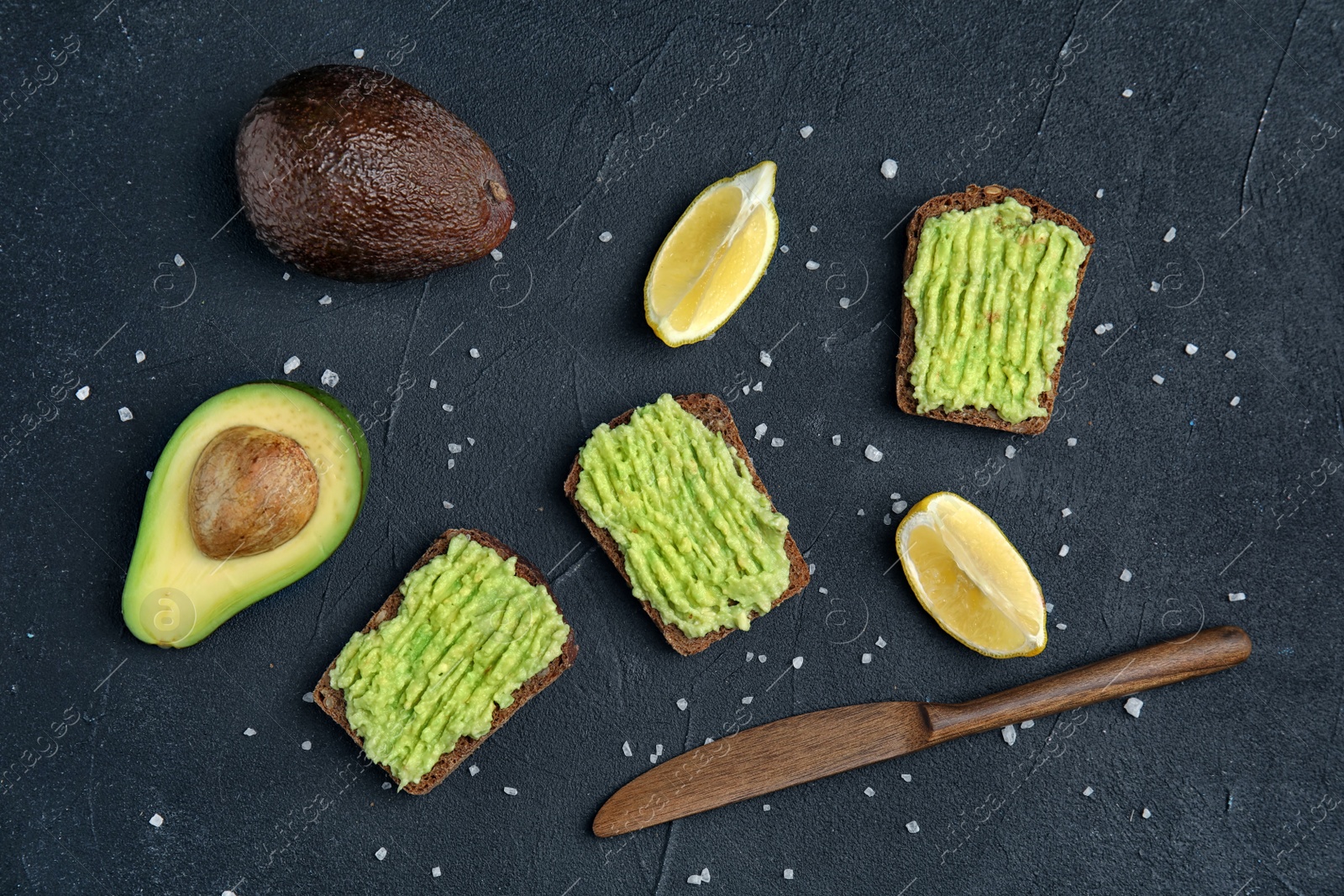 Photo of Flat lay composition with crisp rye toasts and avocado on dark table