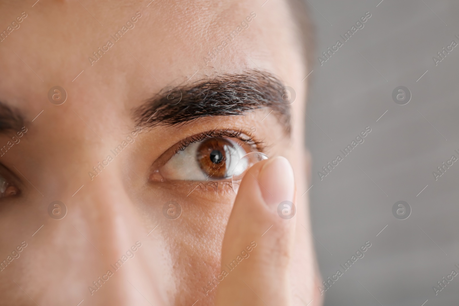 Photo of Young man putting in contact lens, closeup