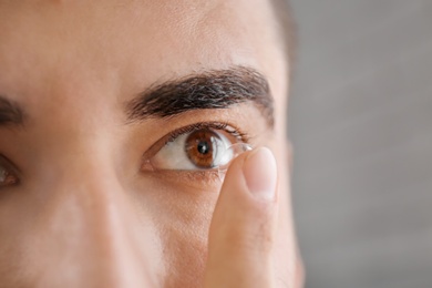 Young man putting in contact lens, closeup