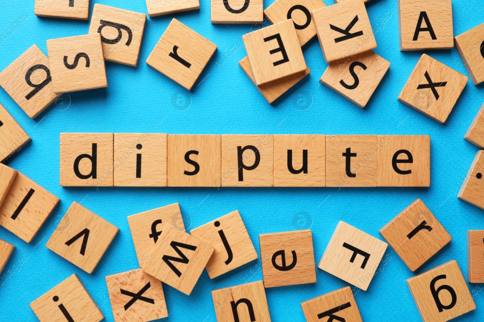 Photo of Word Dispute made with wooden cubes on light blue background, flat lay