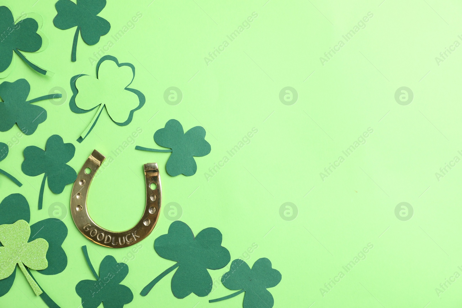 Photo of Flat lay composition with clover leaves and horseshoe on green background, space for text. St. Patrick's day